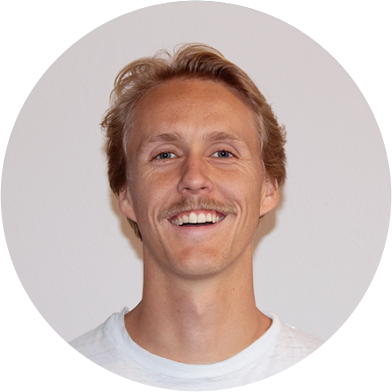 nate Smiling person with light hair and a mustache, wearing a white shirt, against a plain background.